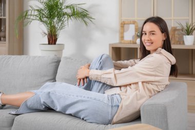 Gri kanepede uzanmış güzel bir genç kadın.