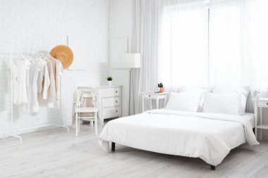 Yatak odasının içinde elbise askısı, çekmece ve lamba var.