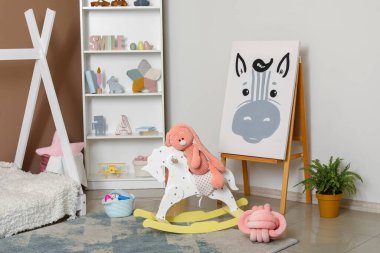 Raflar ve sallanan at modern çocuk odasının içinde.