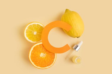 Kağıt harf C, gerekli yağ şişesi ve renklendirilmiş taze narenciye meyvesi.