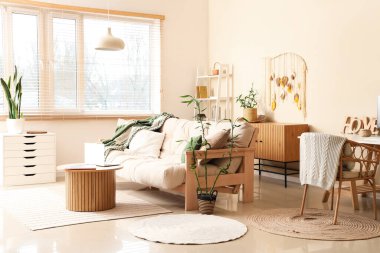 Ekoseli rahat kanepe, dizüstü bilgisayarlı kahve masası ve oturma odasında bambu bitkisi.