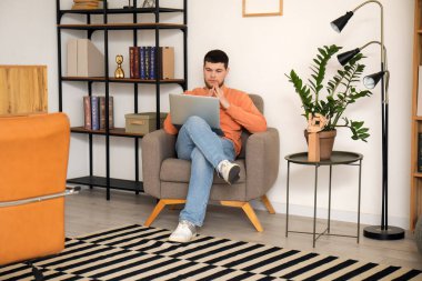 Ofisteki koltukta dizüstü bilgisayar kullanan genç sakallı adam.