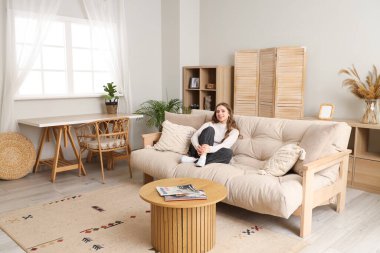 Evdeki yumuşak kanepede oturan genç kadın.