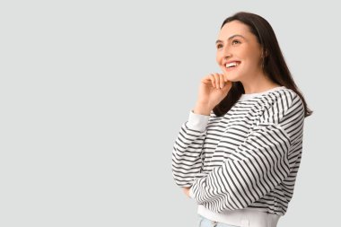 Gri arka planda gülümseyen genç kadın