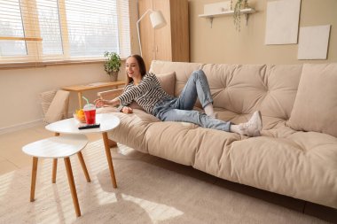 Genç bir kadın evdeki masada kaseden lezzetli cipsleri alıyor.