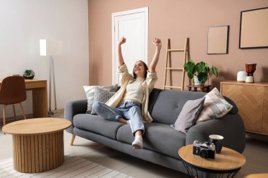 Bej oturma odasındaki kanepede dinlenen genç ve güzel bir kadın.