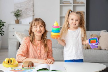 Dadı ve küçük kız evde oyuncaklarla oynuyorlar.