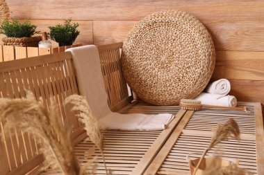 Havlulu Rattan puf ve saunadaki ahşap bankta masaj fırçası.