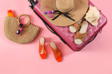 Bavullu kompozisyon, şık plaj aksesuarları ve pembe arka planda seks oyuncakları.