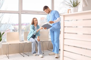 Klinikte bekleyen bir hastası olan bir resepsiyonist.