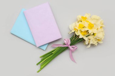 Üzerinde nergis çiçekleri ve gri arka planda not defteri olan kompozisyon. Üst görünüm