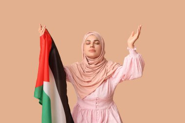 Filistin bayrağıyla bej arka planda dua eden güzel Müslüman kadın. Üzüntü konsepti