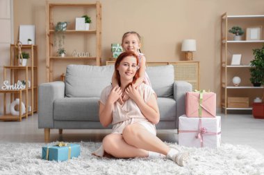 Küçük kız annesine sarılıyor ve onu hediye kutusuyla karşılıyor. Anneler Günü