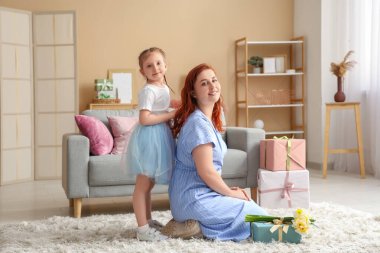 Oturma odasında annesinin saçına dokunan küçük bir kız. Anneler Günü