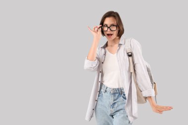 Beyaz arka planda sırt çantası olan şaşırmış bir kız öğrenci.