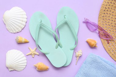 Şık plaj aksesuarları ve leylak arka planda deniz kabukları olan kompozisyon
