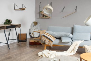 Kanepesi, rafları ve kırık aynası olan dağınık bir oturma odası.