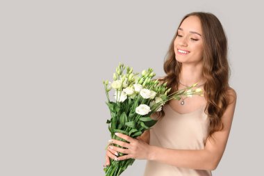 Işıklı arka planda Eustoma çiçekleri olan güzel genç bir kadın.