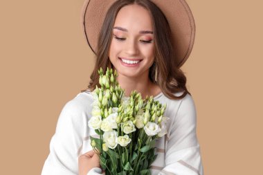 Kahverengi arka planda Eustoma çiçekleri olan güzel bir genç kadın, yakın plan.