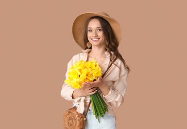 Kahverengi arka planda nergisleri olan güzel genç bir kadın.