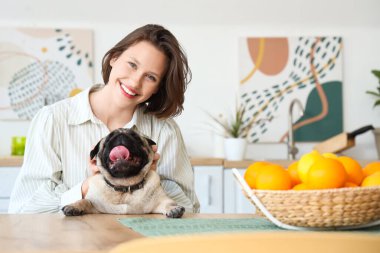 Mutfaktaki masada oturan sevimli köpekli genç kadın.