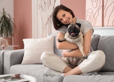 Evdeki kanepede oturan sevimli köpekli genç kadın.