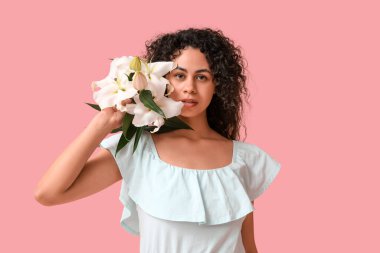 Pembe arka planda beyaz zambak çiçekleri olan güzel bir Afro-Amerikalı kadın.