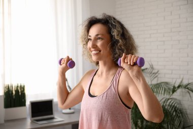 Evde dambıl eğitimi alan mutlu, olgun bir kadın.