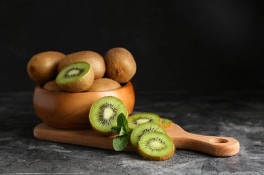 Tahta tahta ve kase ve siyah arka planda taze kivi.