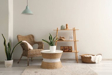 Hasır koltuğu, sehpası ve çiçekleri olan şık bir oturma odası.