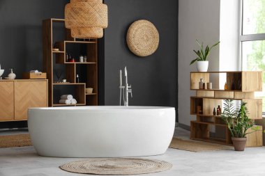 Küvetli, ahşap mobilyalı ve çiçekli modern banyo.
