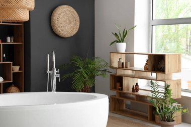 Küvetli, ahşap mobilyalı ve çiçekli modern banyo.