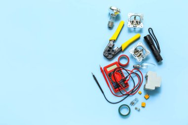 Electrician's tools, light bulb and electronics on blue background clipart