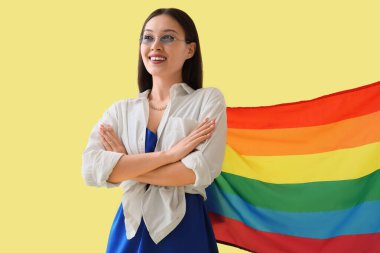 Female Asian fashion designer with LGBT flag on yellow background clipart