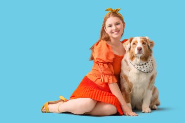 Mavi arka planda şirin Avustralya çoban köpeği olan genç bir kadın.