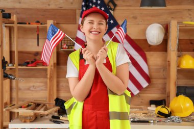 Atölyede ABD bayraklı genç bayan marangoz. İşçi Bayramı kutlamaları