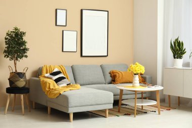 Oturma odasında rahat bir kanepe, sehpa ve vazo çiçekleri var.