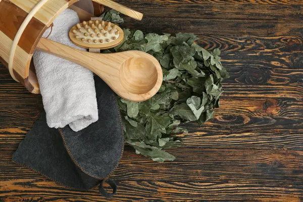 Tahta arka planda sauna için aksesuarlarla çevrilmiş kova.