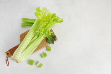 Beyaz zemin üzerinde taze yeşil kereviz demeti ile ahşap tahta tahta
