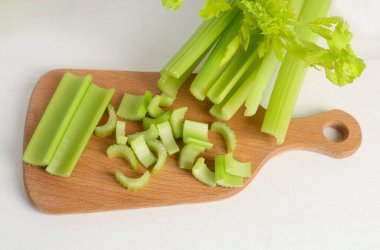 Beyaz zemin üzerinde taze yeşil kereviz kesilmiş ahşap tahta.