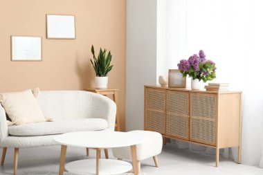 Beyaz kanepe ve sehpanın yanındaki çekmecelerde leylak dalları olan şık bir oturma odası.