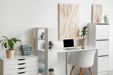 Modern işyeri, dizüstü bilgisayar ve resimli hafif ofis.