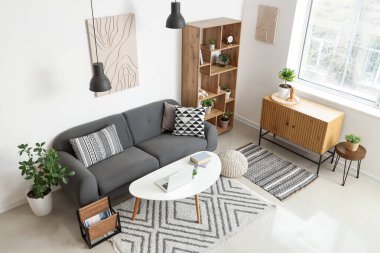 İçinde siyah kanepe, sehpa, çekmeceler ve raf ünitesi olan şık bir oturma odası.