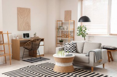 Gri kanepesi, sehpası, işyeri ve raf ünitesi olan şık bir oturma odası.