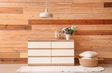 Şık ahşap dolap, yastıklar ve içinde çiçekler olan vazo.