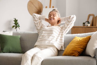 Şık oturma odasındaki kanepede dinlenen genç bayan.