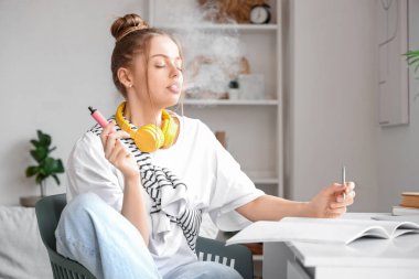 Tek kullanımlık elektronik sigara içen ve not defterine yazan genç bir kadın.