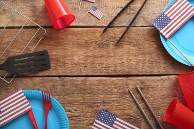 Barbekü malzemelerinden, yemek takımlarından ve ahşap arka planda Amerikan bayraklarından yapılmış çerçeve. Amerikan Bağımsızlık Günü