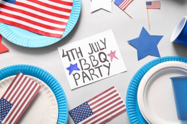 Gri arkaplanda Bağımsızlık Günü kutlamaları için 4 Temmuz barbekü partisi, yemek takımı ve ABD bayrakları yazılı kart