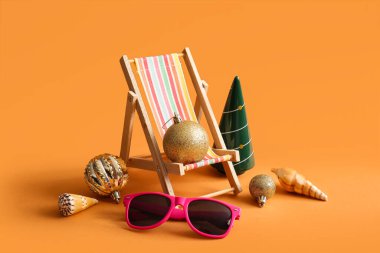 Renkli arka planda mini şezlonga, güneş gözlüğüne ve Noel süslemelerine sahip kompozisyon